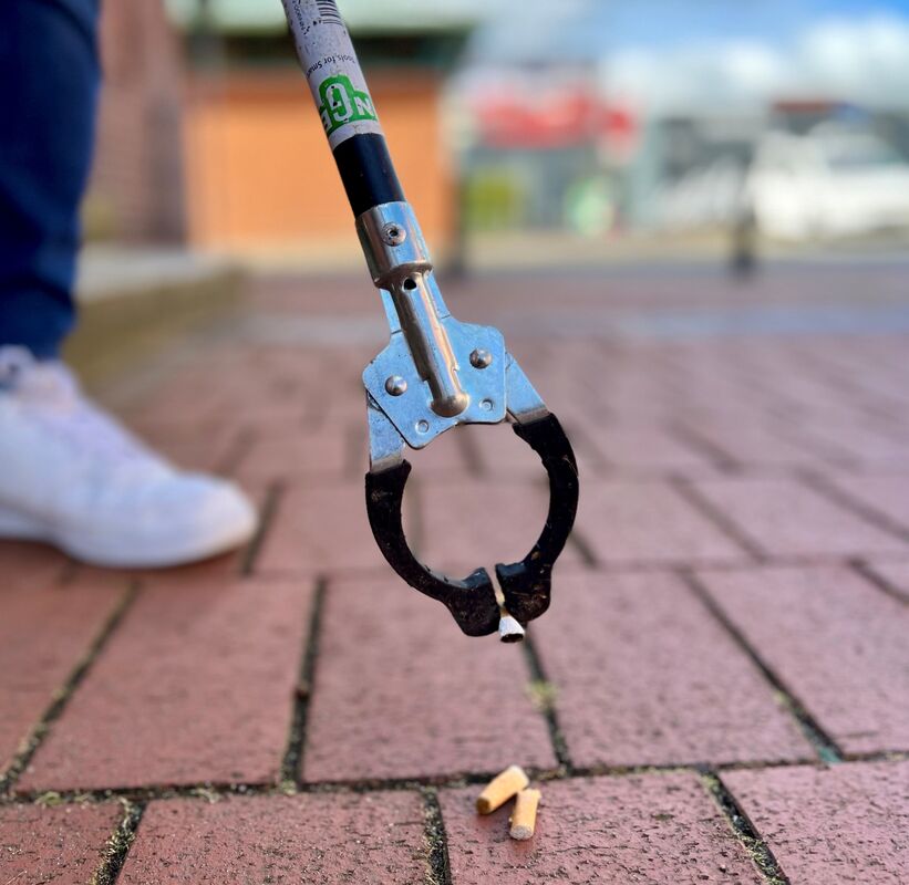 Kippen werden aufgehoben mit einer Müllzange